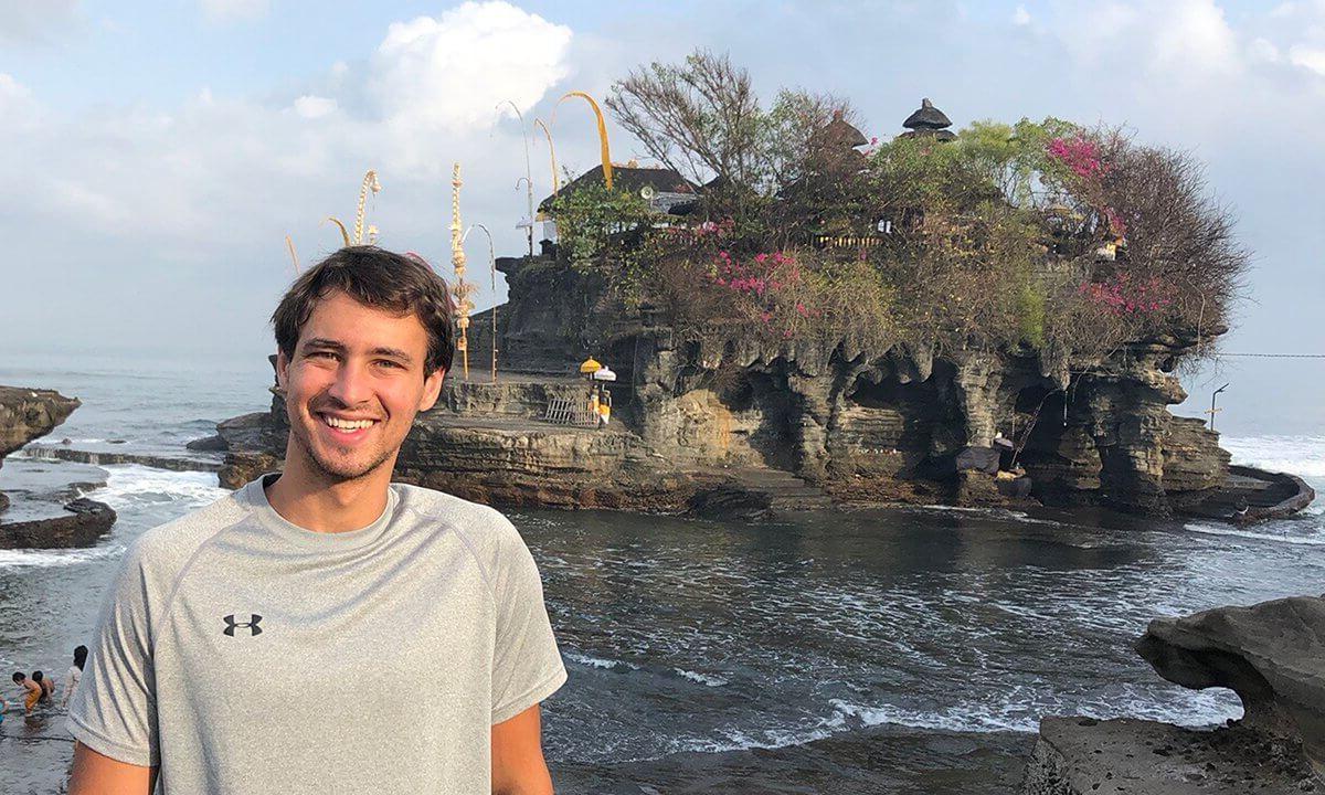 A man posing in front of a scenic island background.